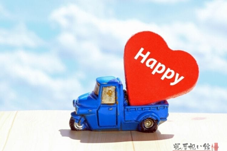 青いミニチュアのトラックの上にhappyと書かれた木製の赤いハートが乗っている