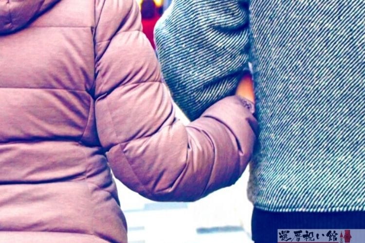 腕組みをして歩く男女の後ろ姿