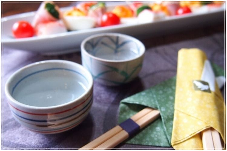 小さなてまり寿司と日本酒が入った2つのおちょことお箸