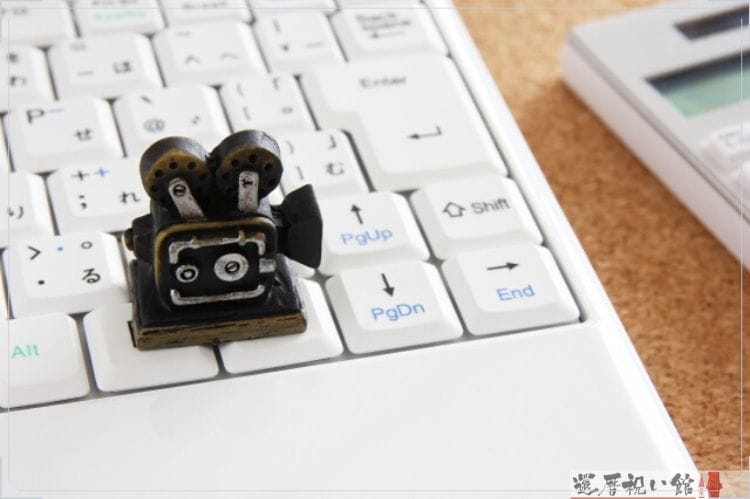 パソコンのキーボードの上にミニチュアの投影機が置いてある