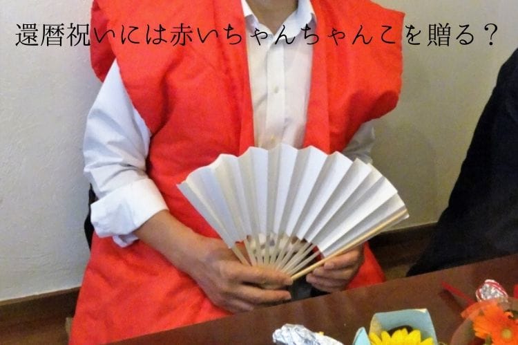 赤いちゃんちゃんこを着て白い扇子を持ったシニア男性