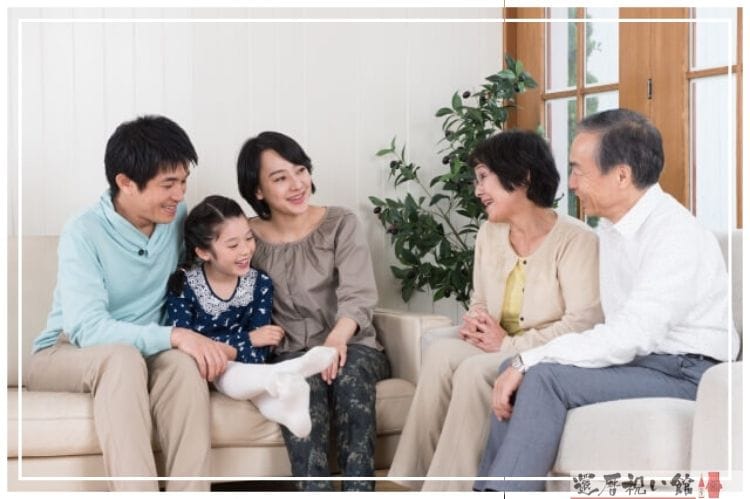 二世帯の家族がソファに座り笑顔で話し合っている様子