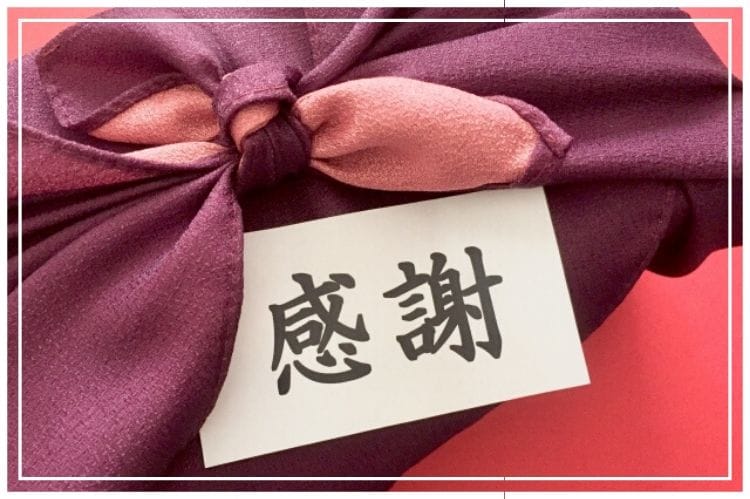 紫の上品な風呂敷に包まれた贈り物と感謝と書かれたメッセージカード