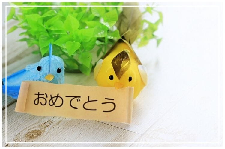 手作りの黄色と水色の小さな鳥のくちばしに【おめでとう】と書かれた紙がくっついている