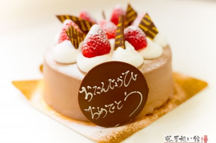 たんじょうびおめでとうと書かれたチョコレートの板がつき、上にいちごが乗ったケーキ