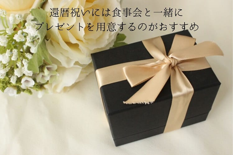 黒い箱に薄いピンクのリボンがついたプレゼントボックスと白い薔薇の花束