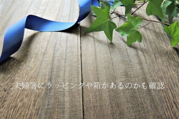 木の板の上に植物の葉っぱと青いリボンが置かれている