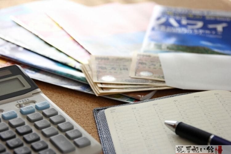 ハワイの旅行パンフレットと電卓やお札、手帳