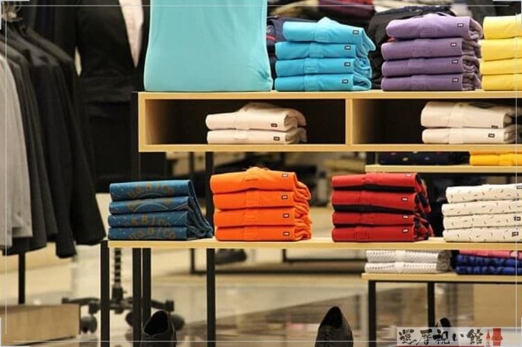 メンズファッションショップで、男性用のポロシャツがたたんで陳列されている様子