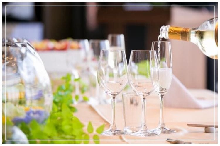 ホテルのビッフェルームのテーブルに置いてあるグラスにシャンパンをそそぐ様子