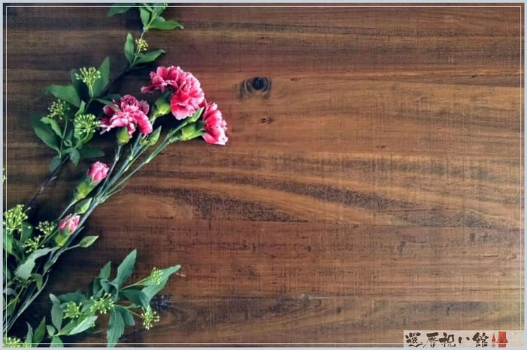 木の板の上に濃いピンク色のカーネーションが数本置かれている