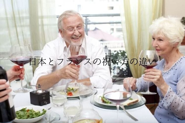 外国のシニア夫婦がワインを片手にテーブルで食事をしている様子