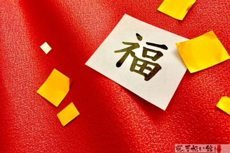 赤い布の上に金色の四角い紙飾りがまばらにちらばっていて、その真ん中に「福」という文字がある