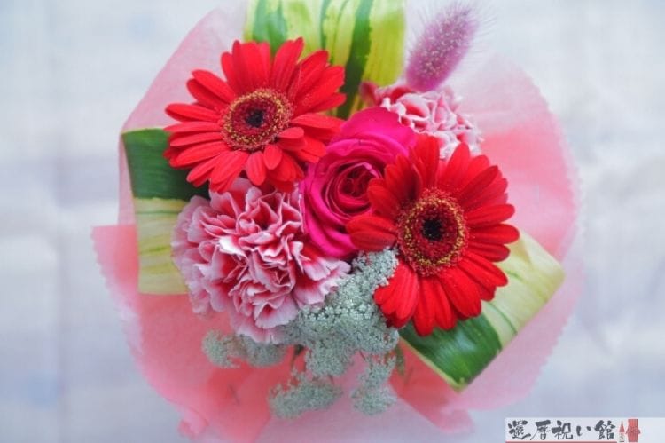 マーガレットやカーネーションなど赤系の色でまとめられたフラワーギフト