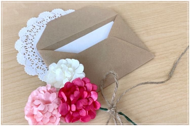 カードが入った茶色の封筒とピンクや白の手づくりの花