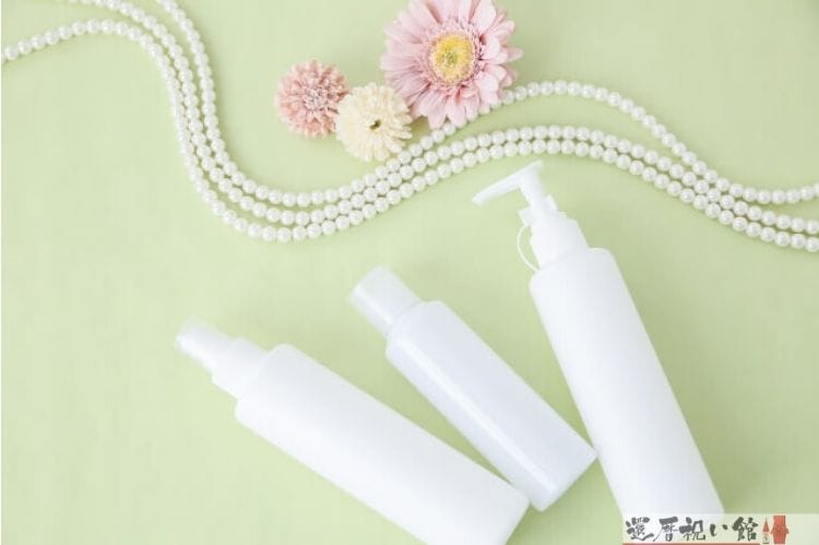 スプレータイプの白いボトル3つと真珠風ネックレスと花