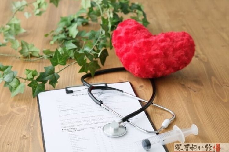赤いハートのクッションと聴診器と注射器、カルテ