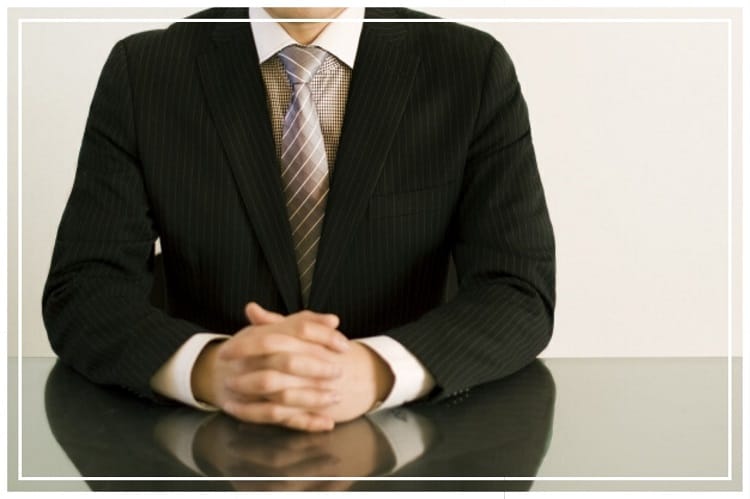 黒いスーツを着てテーブルに座っている男性