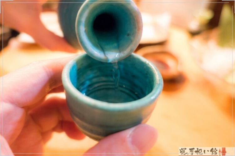 水色の徳利から同じく水色のおちょこに日本酒をついでいる様子