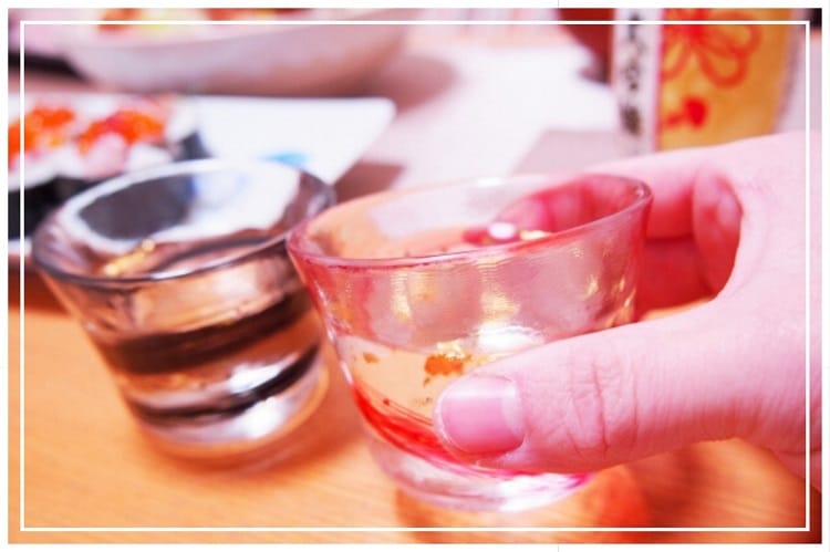 日本酒が入ったグラス製のおちょこで乾杯しようとしている様子