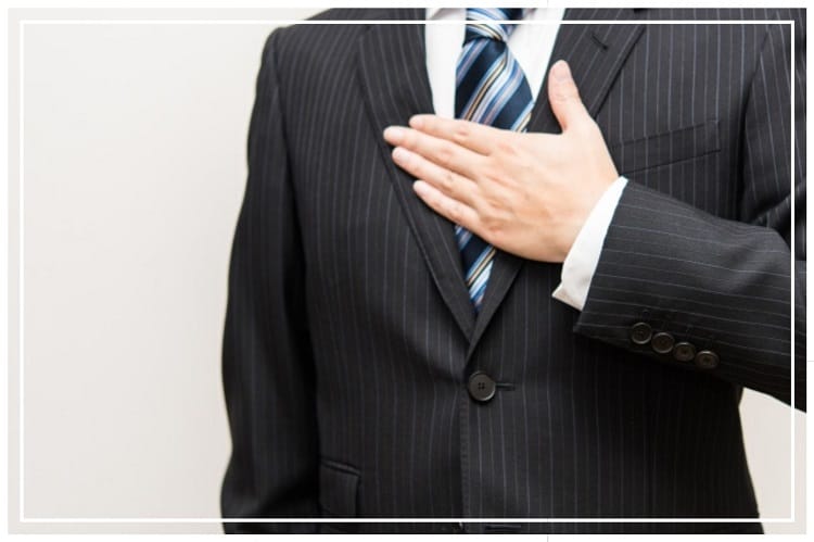 胸に手をあてるスーツを着た若い男性