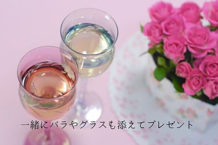お酒が入った小さなグラス2つとピンクの薔薇の花束