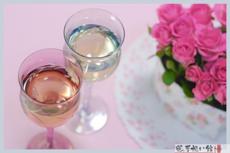 ピンクの薔薇の花束と2つの小さなグラスに注がれた白ワイン