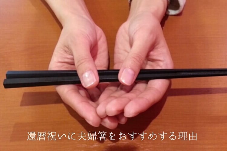 両手で黒い箸を持っている女性