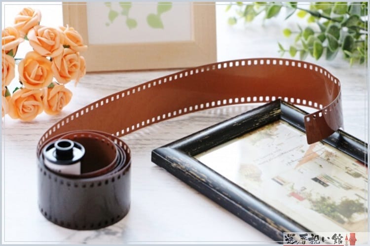 カメラのフィルムと絵が入った写真立てとオレンジ色の薔薇の花束