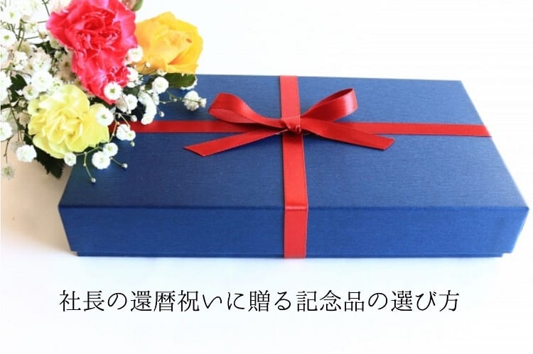 青い箱に赤のリボンがついたプレゼントボックスとピンクやオレンジ、黄色のカーネーション