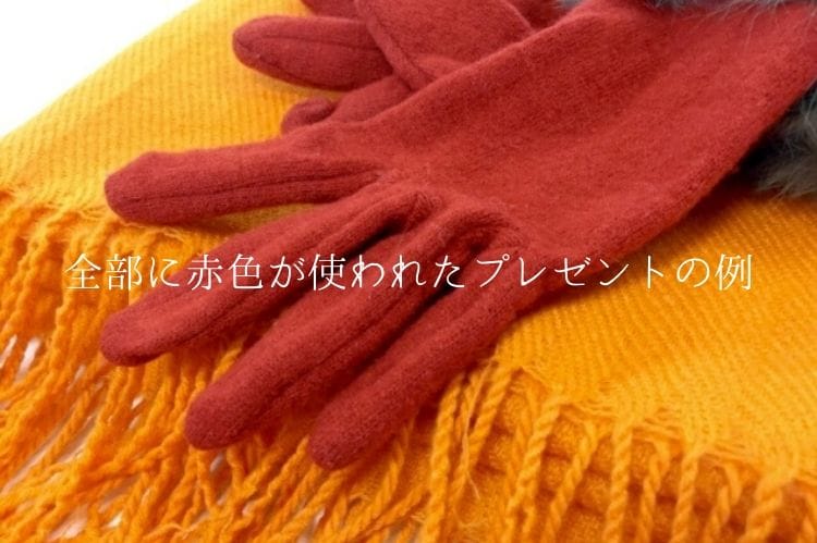 濃いオレンジの毛糸の手袋と鮮やかなオレンジ色のマフラー