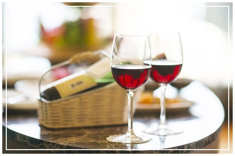 テーブルの上に食事やワインの瓶、赤ワインが入ったグラス2つが置いてある様子