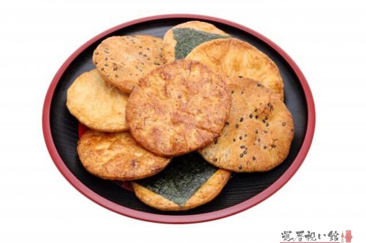 黒いお盆の上に乗った様々な種類の丸せんべい