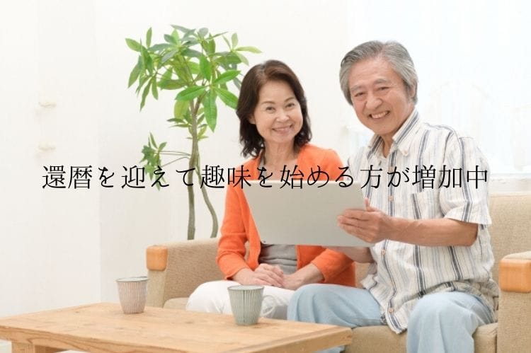 シニア夫婦がソファに座り笑顔でタブレットを扱っている様子