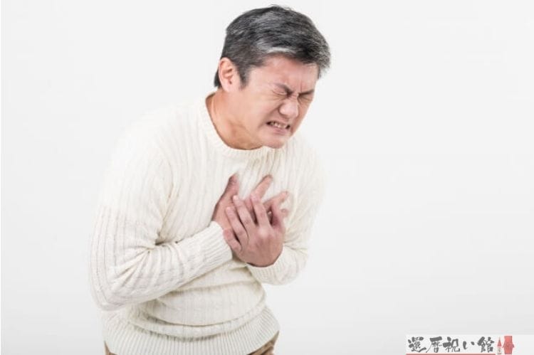 胸の当たりが苦しくなってしまいその箇所を手で押さえ苦しんでいるシニア男性