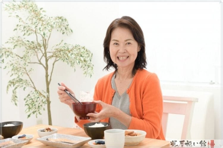 和食のごはんを食べるシニア女性
