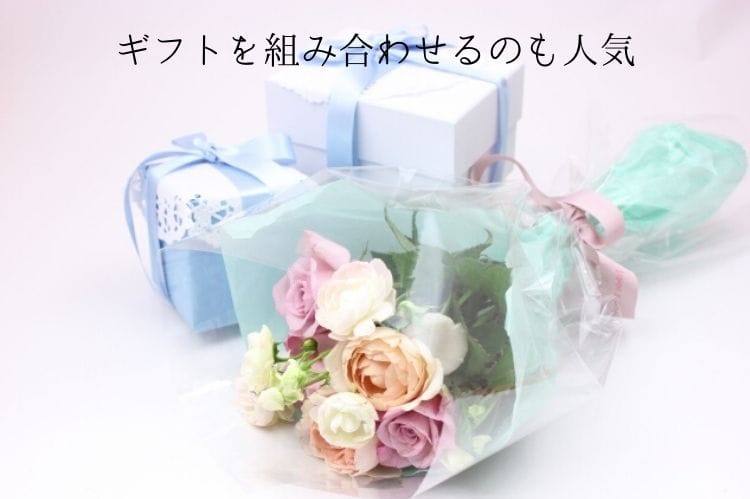 水色ベースのプレゼントボックス2個と白やオレンジの薔薇の花束