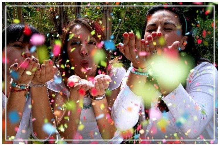 カラフルな紙吹雪をふうっと吹き飛ばしている海外の女性3人