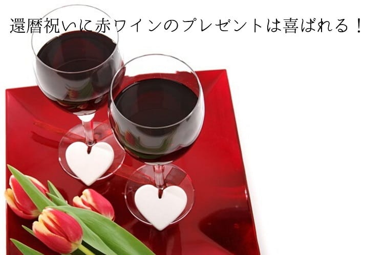 底の部分に白いハートがついているグラス2つに赤ワインが入っていて、その隣にチューリップが2本置いてある