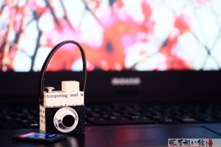 ノートパソコンの上に置いてあるミニチュアのカメラ