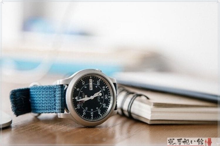 黒の文字盤と青のベルトの腕時計とノート