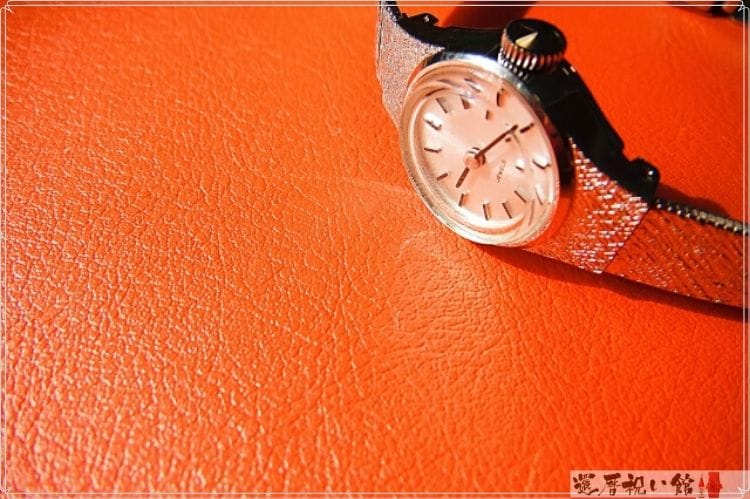 オレンジ色の革の上に置かれた腕時計