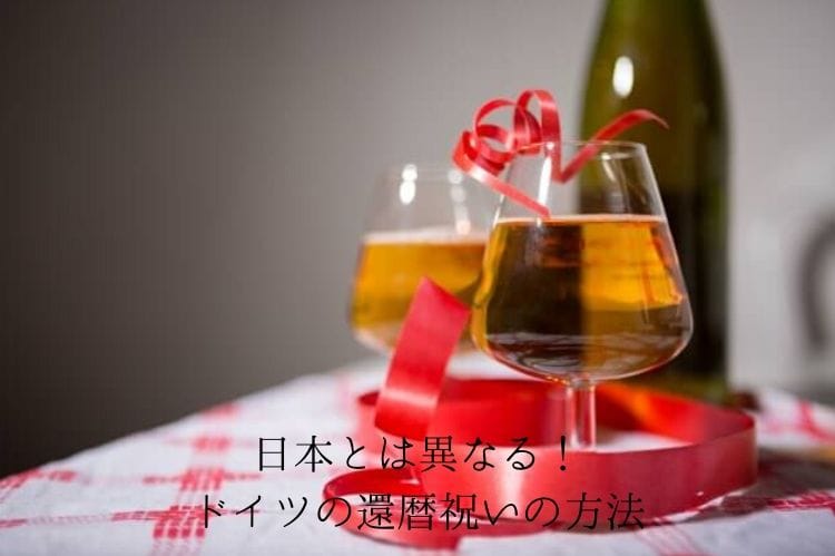 お酒が入った2個のグラスに赤いリボンが巻き付いている