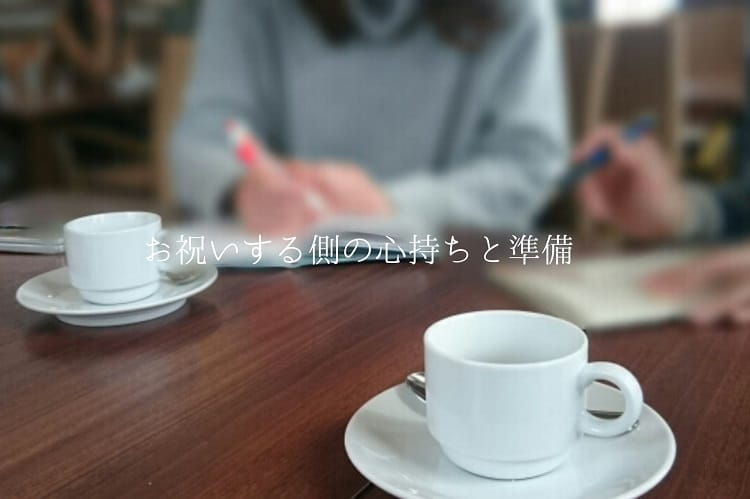 友達と白いマグカップがテーブルにノートを置き何かを話しながら書いている女性