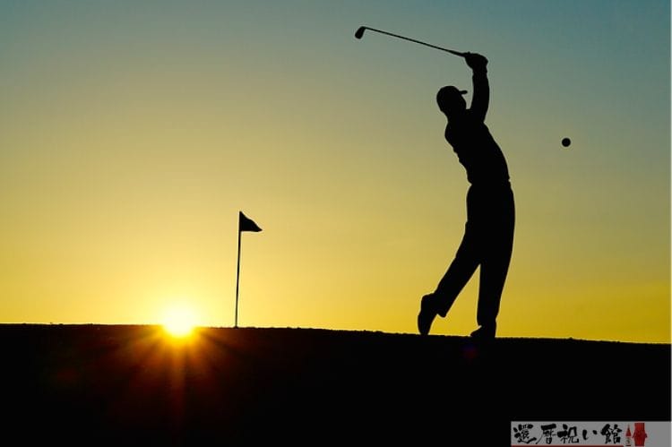 夕日を背にゴルフボールを打っている男性
