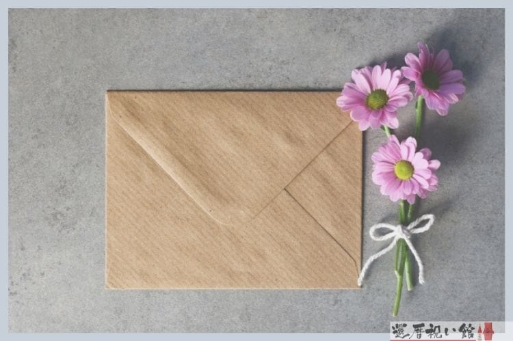 ピンクの小さな花3本と茶色の手紙の封筒