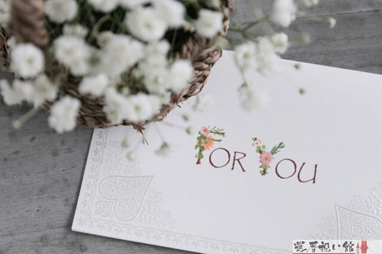 for youと書かれた白いメッセージカードと茶色い籠に入った白くて小さな花