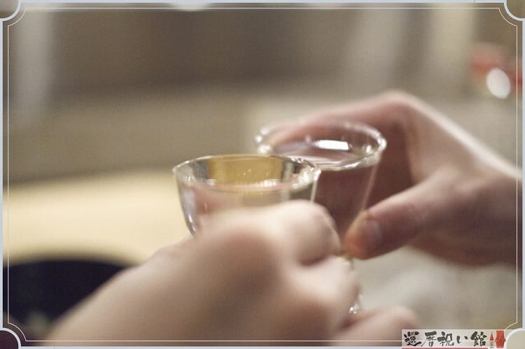 透明のグラスに日本酒を入れて乾杯している様子