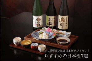日本酒の瓶3本と酒のつまみ、そして4つのおちょこ