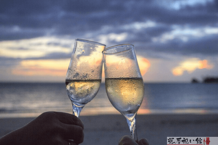 夕日を背景にグラスに入ったシャンパンを乾杯する様子